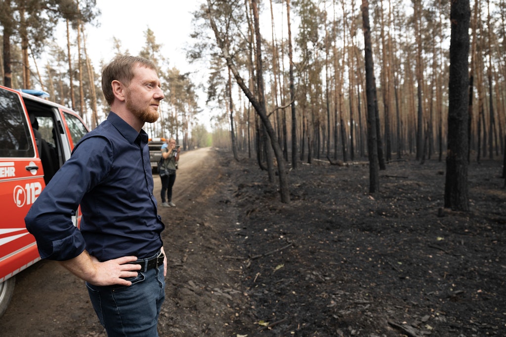 Der sächsische Ministerpräsident Michael Kretschmer begutachtet Schäden in einem an Brandenburg angrenzenden Waldbrandgebiet.