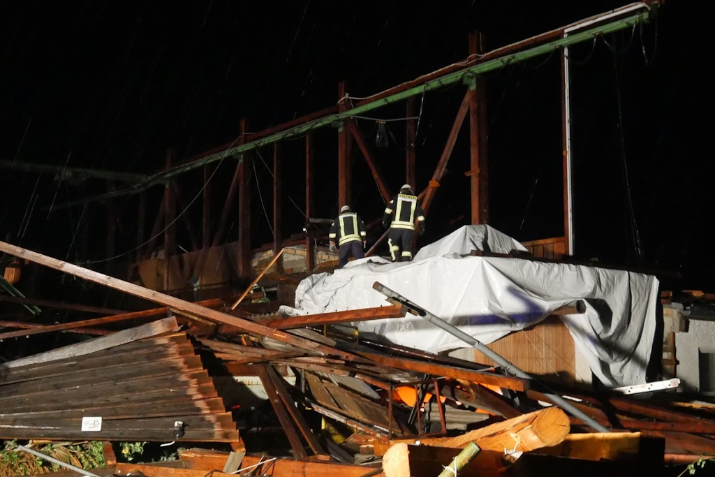 Feuerwehrleute sichern die Überreste einer Lagerhalle. Ein Tornado hatte das Dach von der Materialhalle in Bad Wurzach weggefegt.