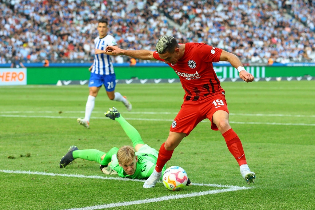 Herthas Torwart Oliver Christensen berührt mit der Hand den Fuß. des Frankfurters Borre. der macht noch einen Schritt und fällt erst dann.
