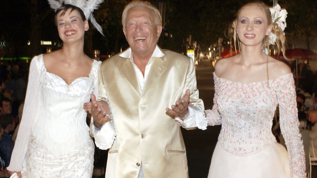 Rolf Eden mit zwei Models auf dem Laufsteg bei der Coral Fashion Show 2002.