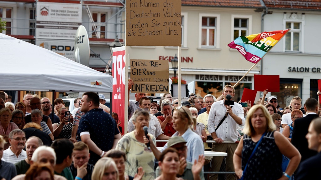 Zuschauer protestieren am Rande der Veranstaltung in Neuruppin.