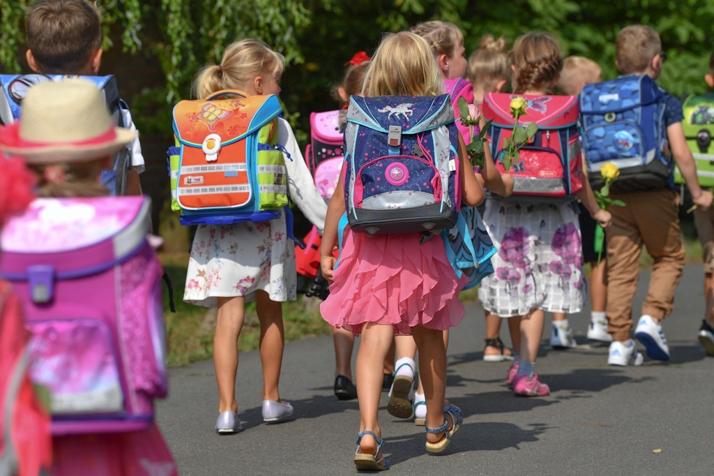 Erstklässler gehen nach einer Einschulungsfeier zur Grundschule.