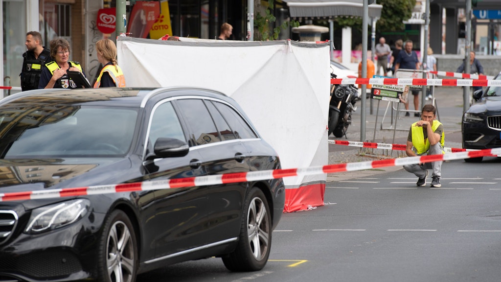 Hinter Sichtschutzwänden liegt an einem Fußgänger-Überweg die Leiche einer Fußgängerin. Die Frau starb am 23. August auf der Residenzstraße nahe dem Franz-Naumann-Platz, als sie von einem Pkw (li.) erfasst wurde.