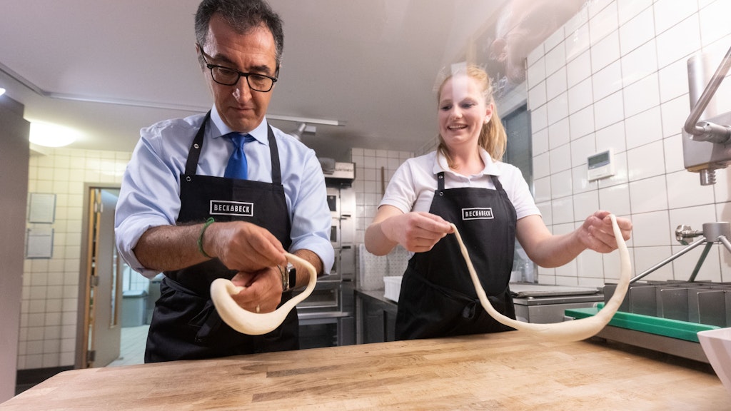 Gar nicht so leicht! Minister Cem Özdemir versucht sich in der Großbäckerei BeckaBeck am Brezel formen. Neben ihm Luisa Beck, Tochter des Bäckerei-Chefs. 