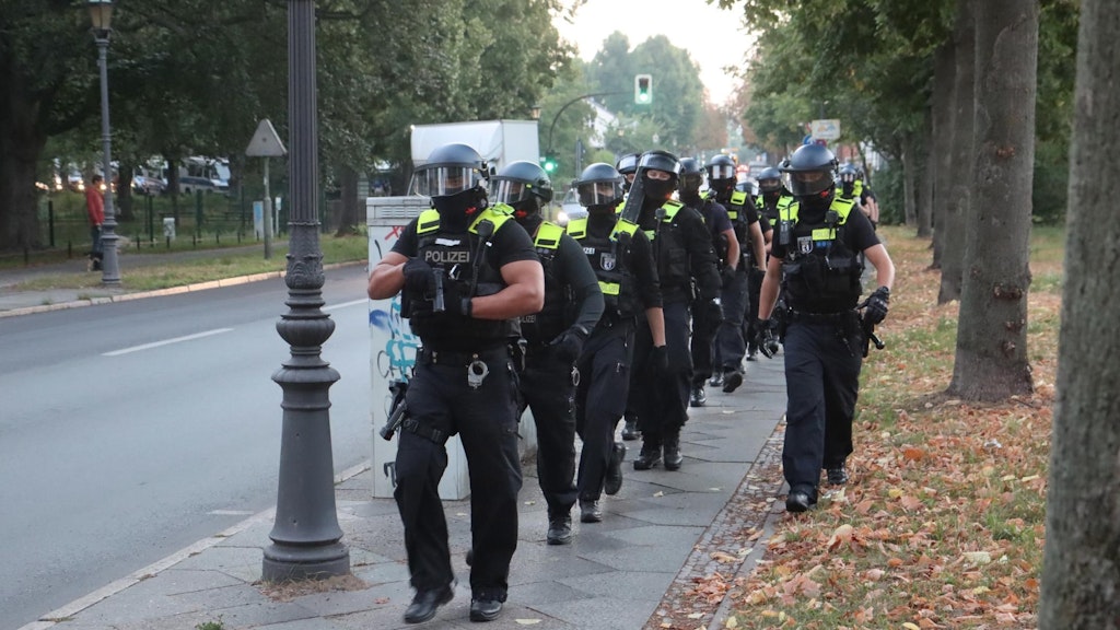 Polizei im Gänsemarsch auf dem Weg zur Remmo-Villa. Der Beamte an der Spitze hat seine Pistole gezogen.