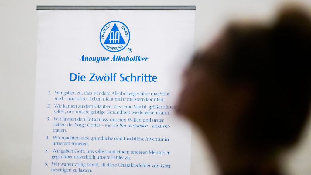 „Wir geben zu, dass wir dem Alkohol gegenüber machtlos sind …“ Auf einem Aufsteller werden die zwölf Schritte der Anonymen Alkoholiker gezeigt.