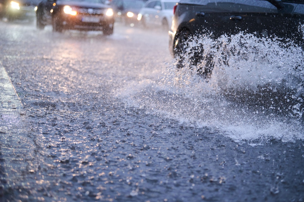 Autos fahren bei starkem Regen durch tiefe Pfützen, die sich auf der Fahrbahn gebildet haben. Nach schweren Regenfällen und Gewittern in Berlin sind größere Schäden etwa durch vollgelaufene Keller weitgehend ausgeblieben. Foto: Annette Riedl/dpa +++ dpa-Bildfunk +++