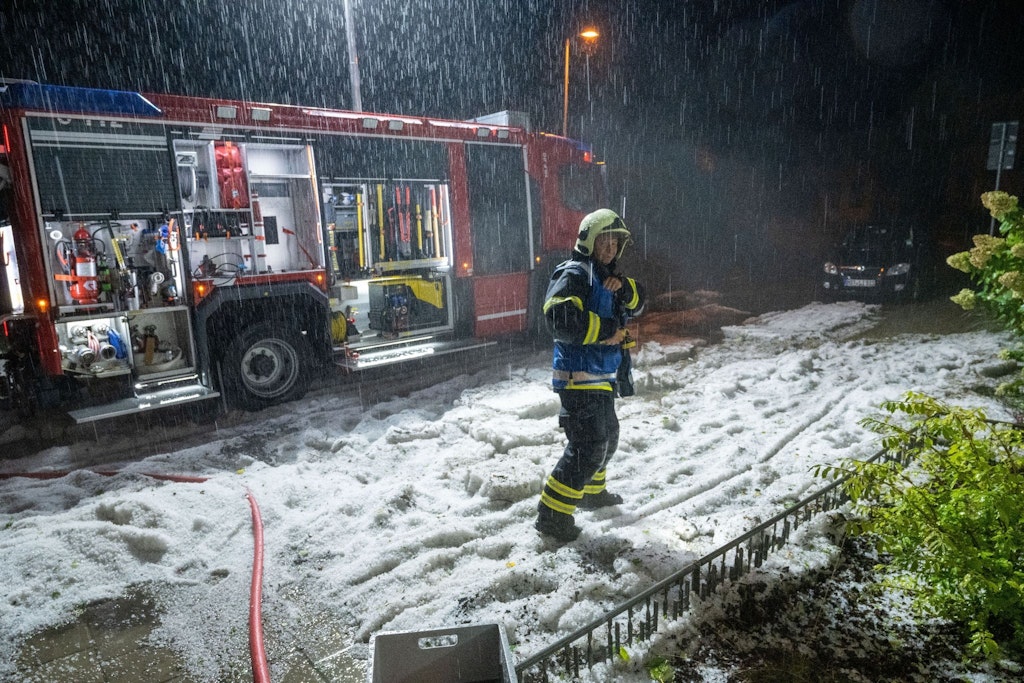 Ein Feuerwehrmann in Stralsund kämpft gegen Hagel und Regen.