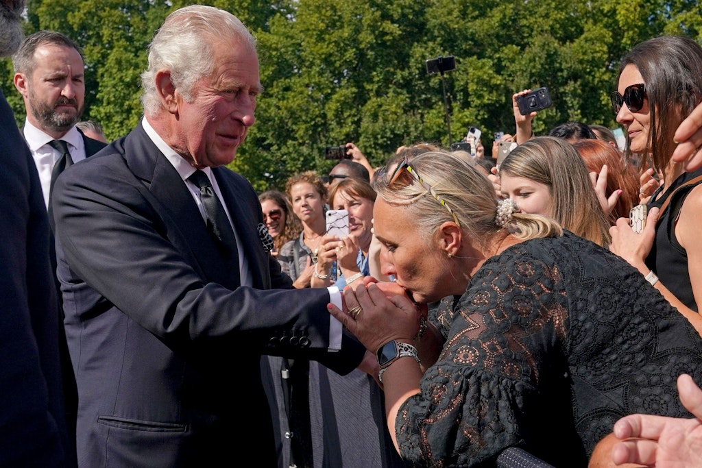 Eine Frau küsst die Hand des neuen Königs.