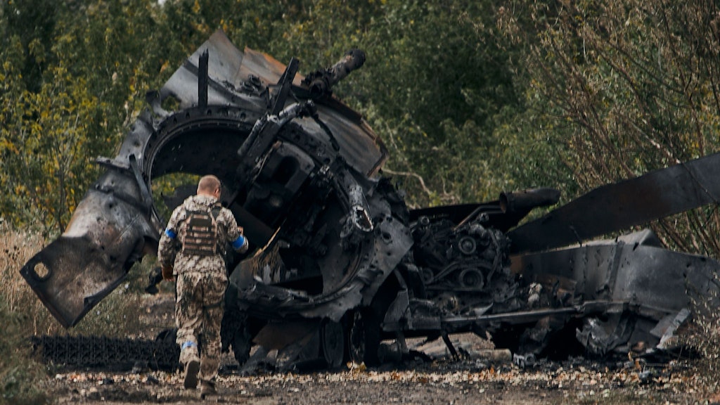 Ein ukrainischer Soldat inspiziert einen zerstörten russischen Panzer im zurück eroberten Gebiet Charkiw.