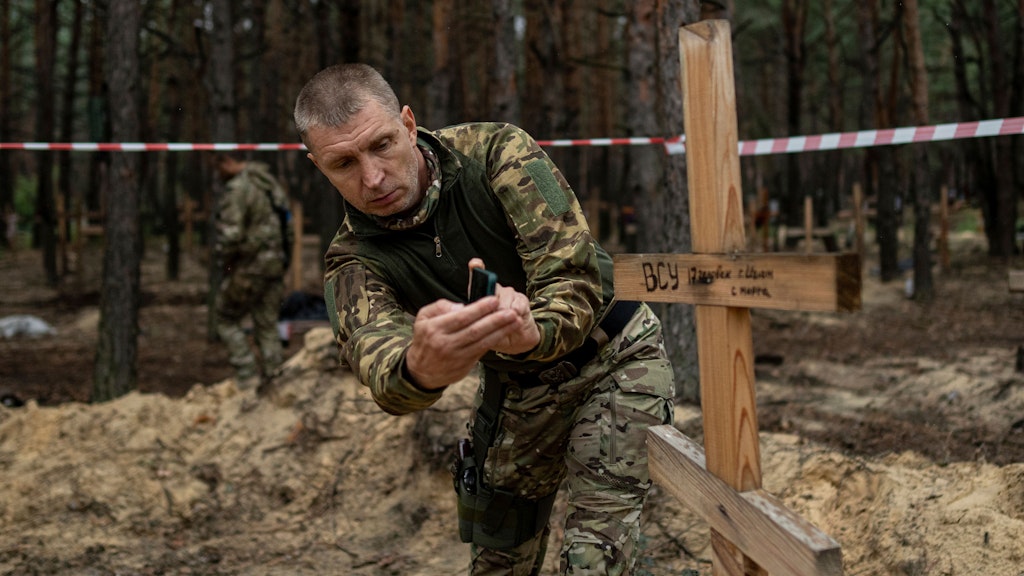 Oleh Kotenko, Vermisstenbeaufragter der Ukraine, fotografiert eines der Grabkreuze bei Isjum. 