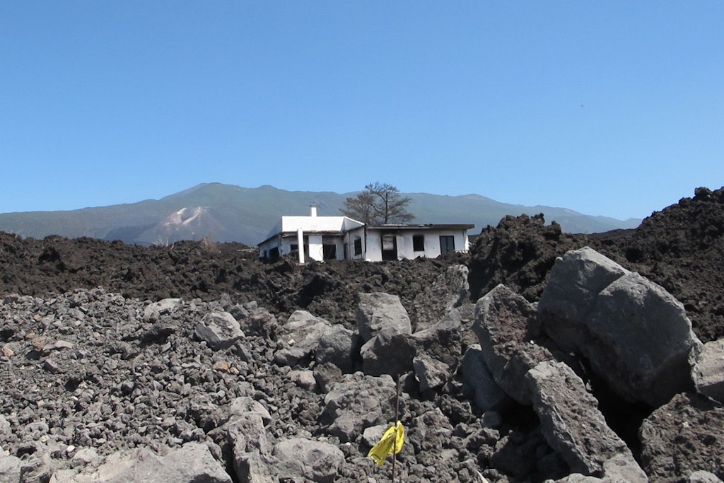 Ein Jahr nach dem Vulkanausbruch steht ein zerstörtes Haus inmitten der erkalteten Lava.