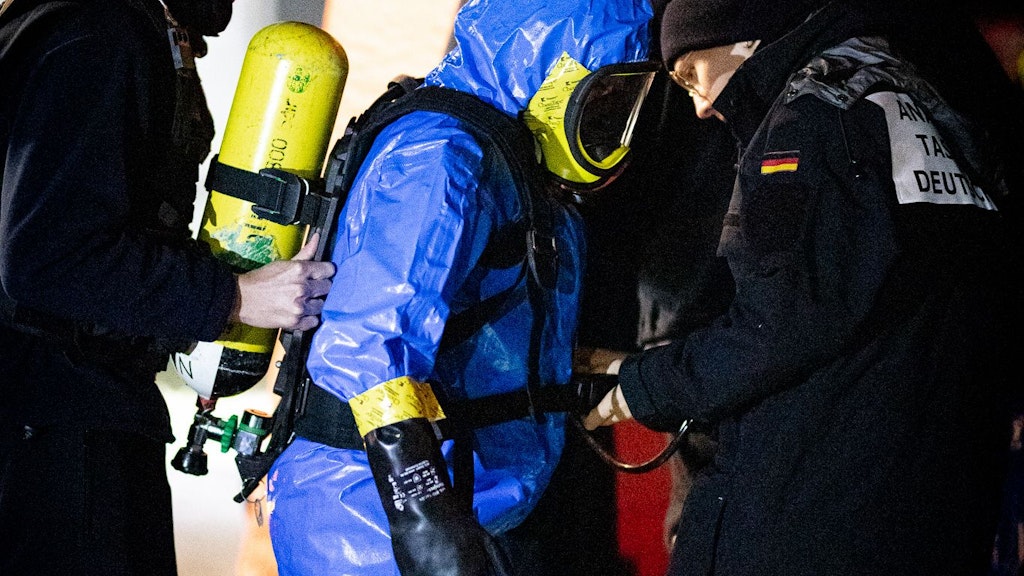 Ein Polizist unter Vollschutz bekommt das Atemgerät angeschnallt - auch das wird geübt. Im Ernstfall muss jeder Handgriff sitzen.