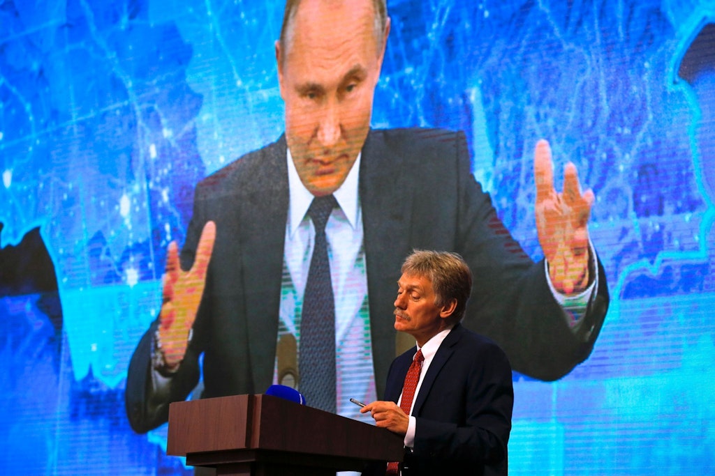 Kremlsprecher Peskow vor einer überdimensionalen Videoprojektion mit Russlands Präsident Wladimir Putin