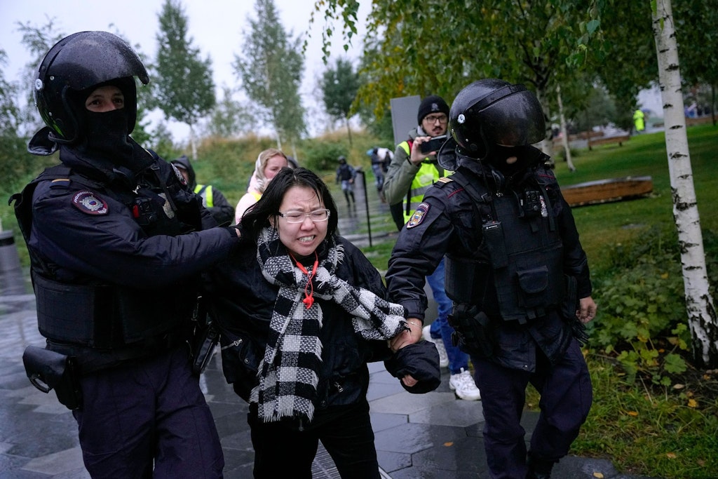 Polizisten in Moskau halten eine Demonstrantin fest.