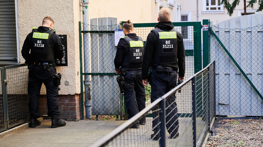 Polizisten stehen vor Wohnhäusern, suchen letzte Personen, die evakuiert werden sollen. 