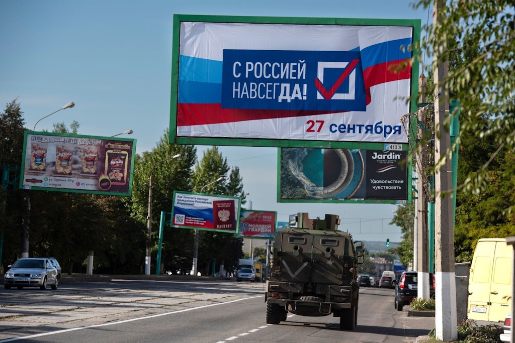 Ein russisches Militärfahrzeug fährt unter einem Plakat entlang, dass zu den Scheinreferenden in den von Russland besetzten Gebieten der Ukraine aufruft.