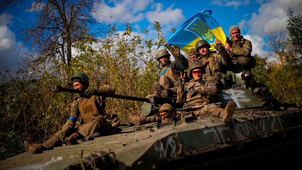 Ukrainische Soldaten halten eine ukrainische Fahne, während sie auf einem gepanzerten Fahrzeug eine Straße zwischen Isjum und Lyman entlangfahren. Derzeit erobert die ukrainische Armee mehr und mehr Gebiete zurück.