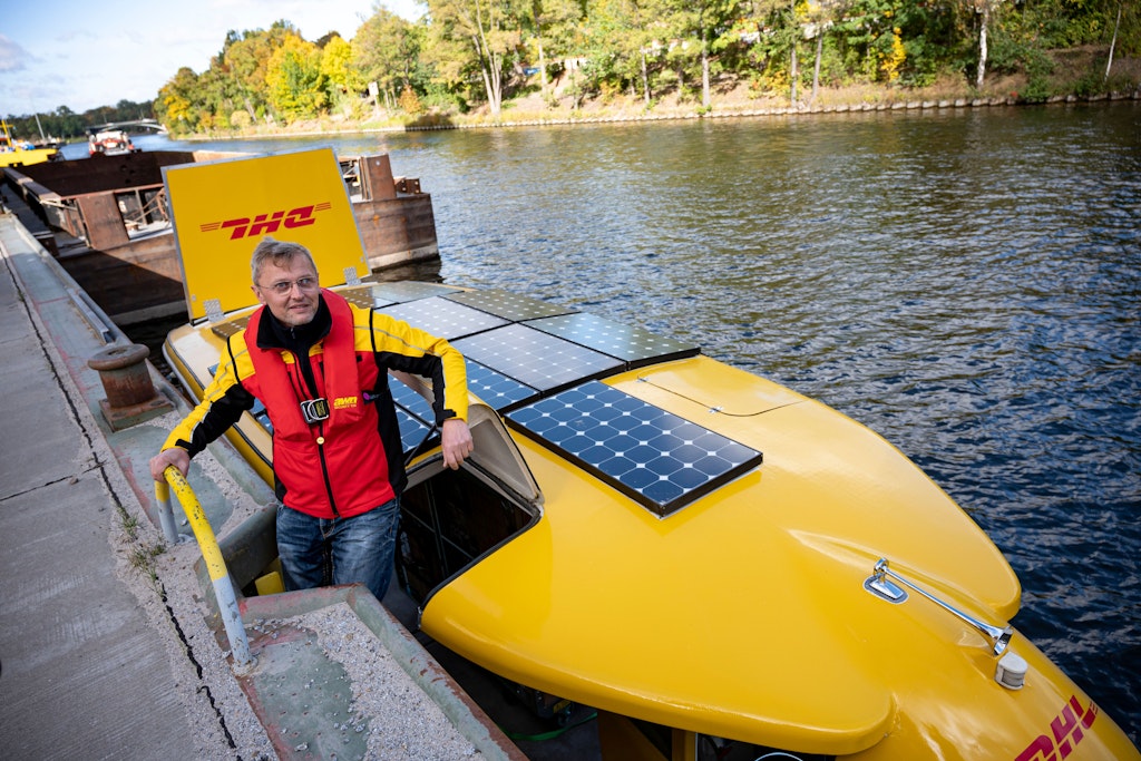 Ein DHL-Mitarbeiter steigt im Westhafen Berlin aus einem Solarschiff. 