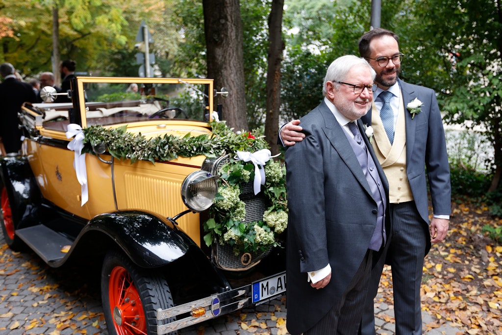 Ex-Mönch Anselm Bilgri (l.) posiert nach der kirchlichen Hochzeit in der alt-katholischen Kirche St. Willibrord mit seinem Mann Markus Bilgri vor einem Oldtimer.