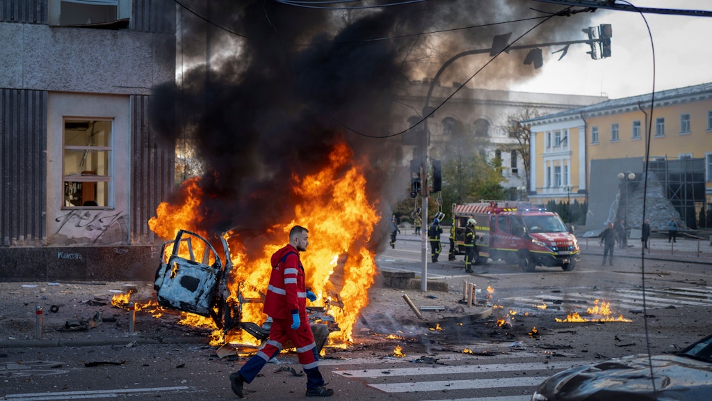 Ein Sanitäter geht in Kiew an einem brennenden Auto nach einem russischen Angriff vorbei.