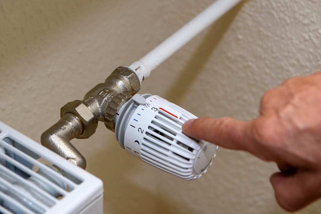 Ein Mann zeigt auf den kleinen Plastikstift auf dem Thermostat.