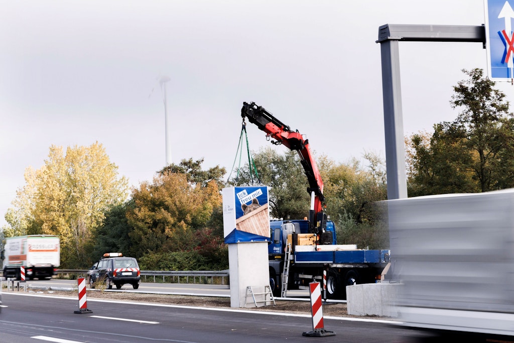 In einer Kiste wird die Figur eines Berliner Bären auf einen Sockel gehoben – bald wird die Figur an einem Autobahnabschnitt auf der Autobahn A114 enthüllt.