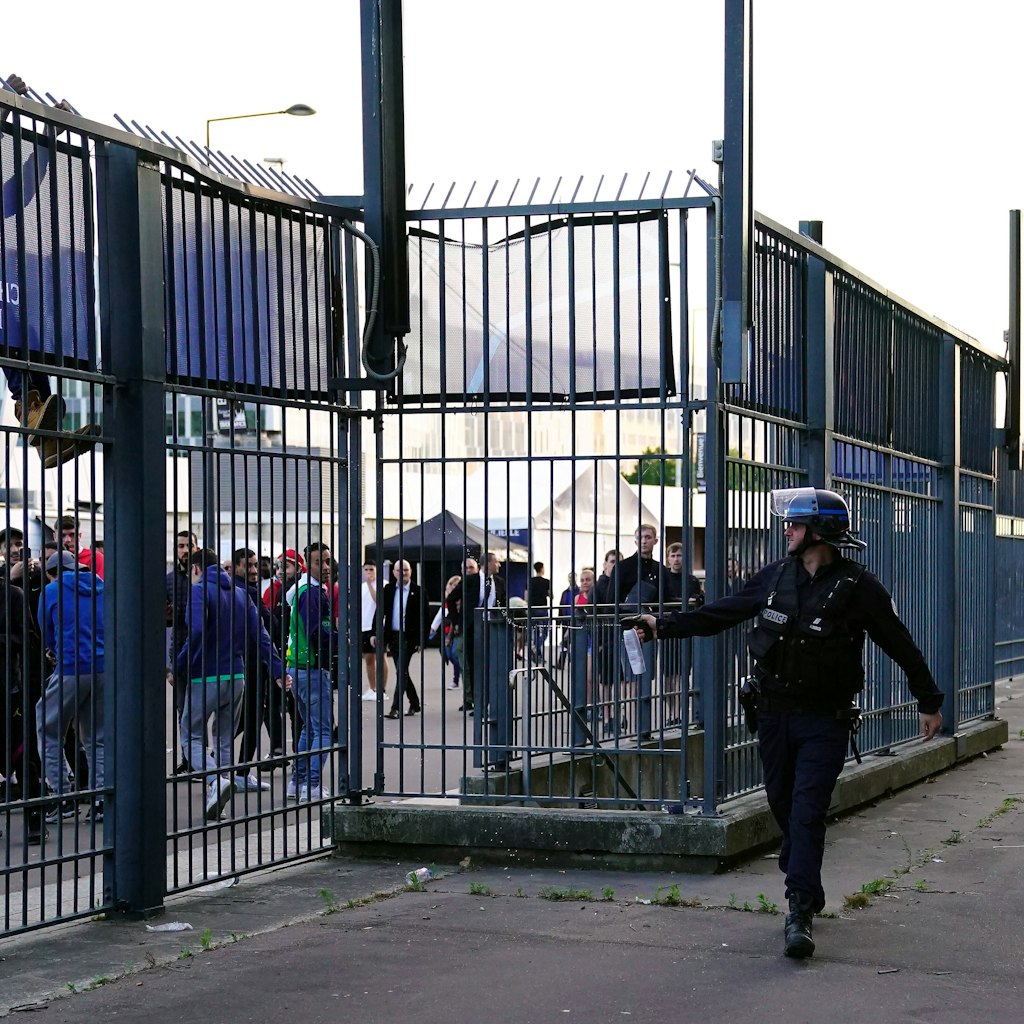 Ein Polizist versucht mit Tränengas die Fans vom Stadionzaun fernzuhalten.