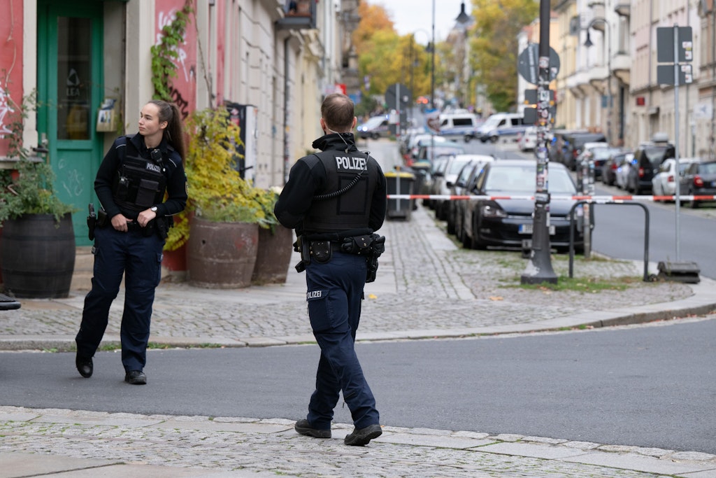 Polizisten stehen im Dresdner Stadtteil Leipziger Vorstadt auf der Rudolf-Leonhard-Straße vor einem Absperrband. Wegen eines Mannes mit einer Pistole, der am Fenster eines Wohnhauses zu sehen ist, gibt es einen Großeinsatz der Polizei. 