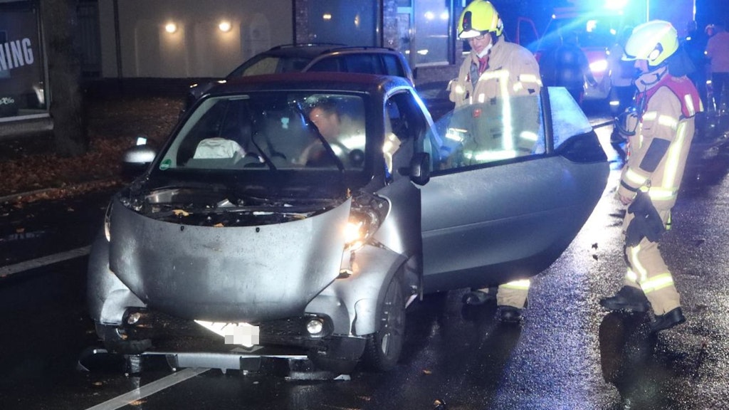 Feuerwehrmänner untersuchen den Unfallwagen.