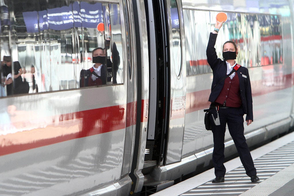 Eine Zugbegleiterin der DB arbeitet in Hose und Jackett.