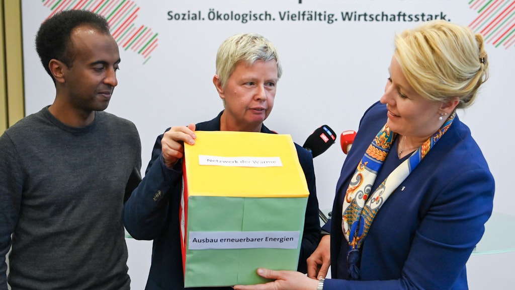 Franziska Giffey (r., SPD), Berlins Regierende Bürgermeisterin, Katina Schubert, Landesvorsitzende der Partei Die Linke, und Philmon Ghirmai, Landesvorsitzender von Bündnis 90/Die Grünen halten ein symbolisches Entlastungspaket in den Händen. 