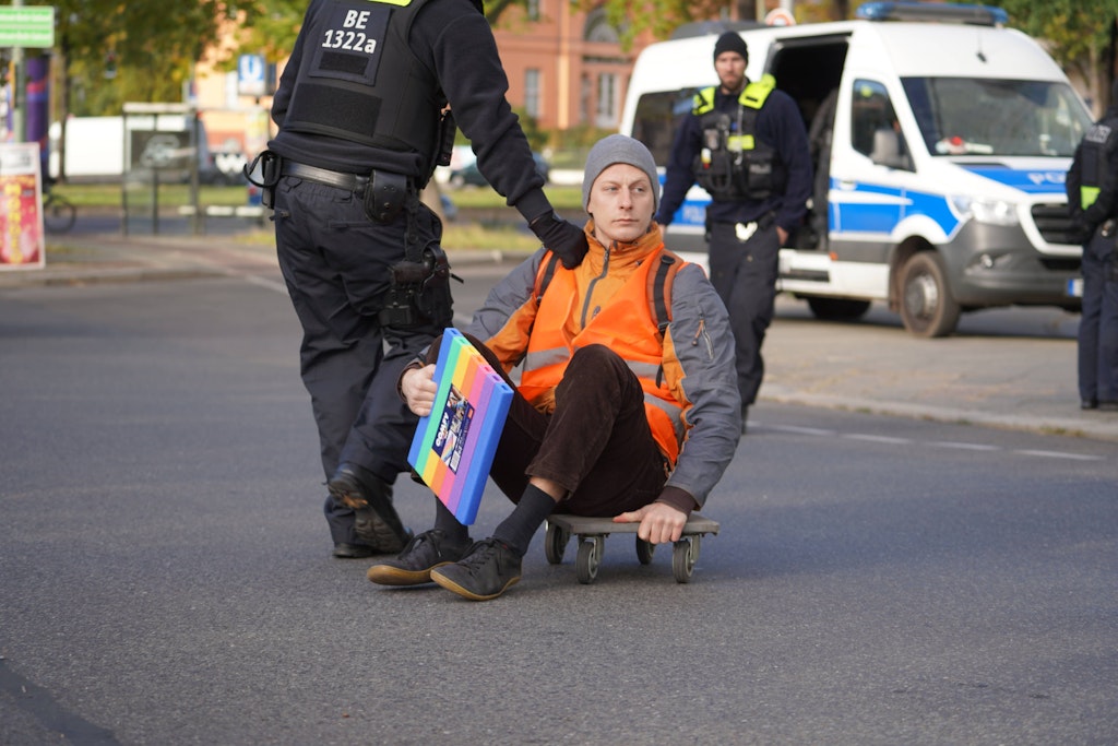 Polizisten nehmen einen Klima-Kleber in Gewahrsam, der die Ausfahrt der Berliner Stadtautobahn A103 in Steglitz blockiert hatte.