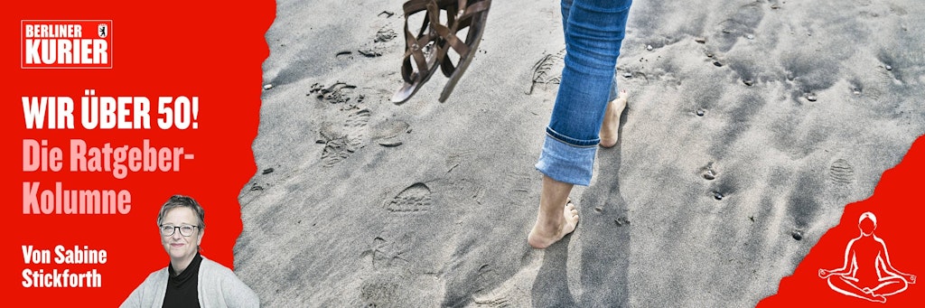 Eine Frau läuft mit nackten Füßen über Sand.
