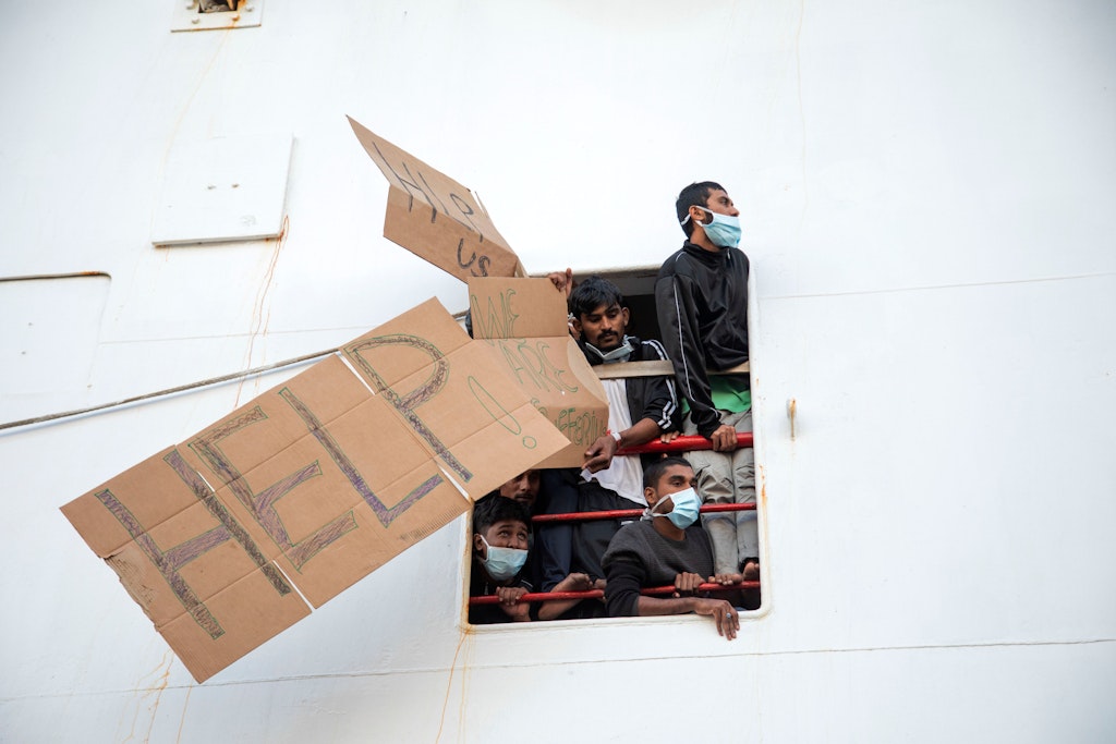Mit Pappschildern bitten die Männer um Hilfe, die im Hafen von Catania auf der Geo Barents festsitzen.