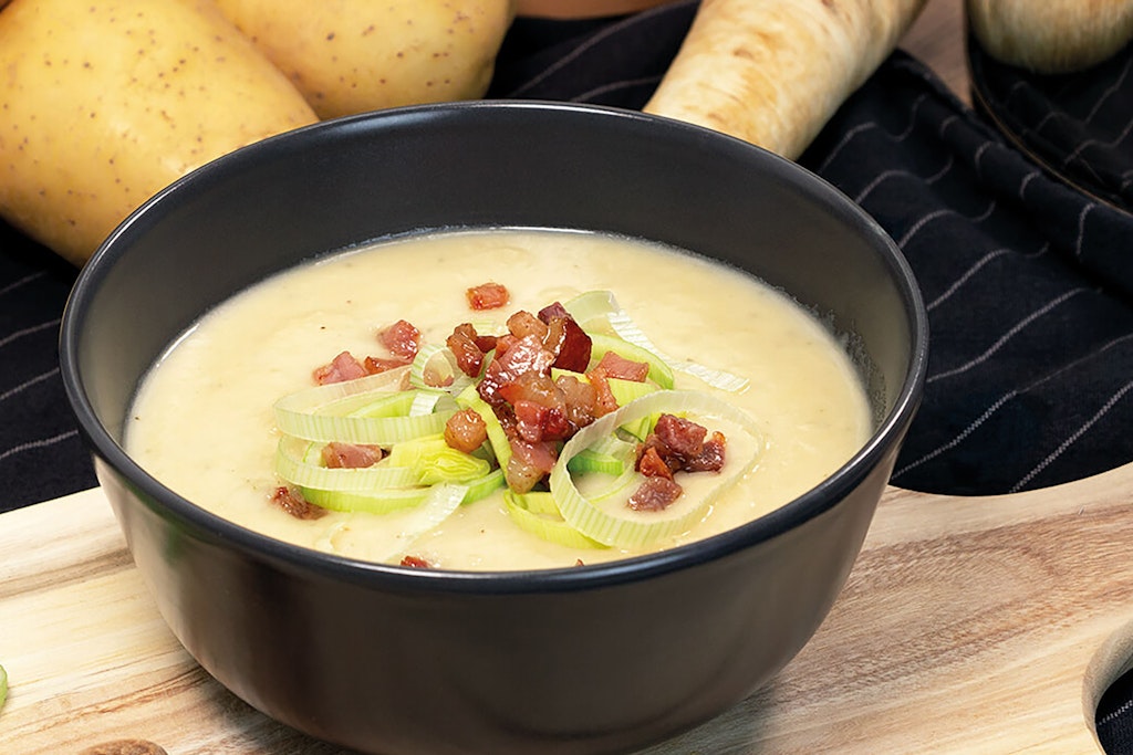 Die Kartoffelsuppe wird mit knusprigem Würfelspeck getoppt. 