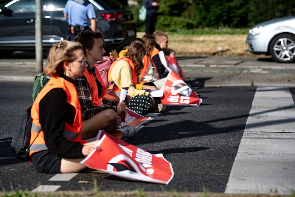 Klimaschutz-Aktivisten der Gruppe „Letzte Generation“ sitzen an der Ausfahrt Halenseestraße der Stadtautobahn. Mehrere Aktivisten haben sich mit Händen auf der Fahrbahn festgeklebt.