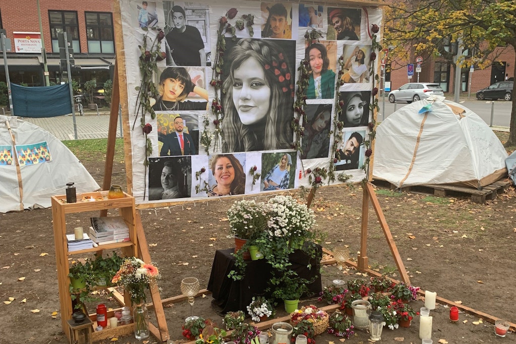 Fotos von jungen Leuten, die im Iran vom Staat umgebracht wurden, im Protest-Camp in Berlin-Mitte. Das Bild in der Mitte zeigt Mahsa Amini, die im Alter von 22 Jahren in der Hand der Sittenpolizei starb.