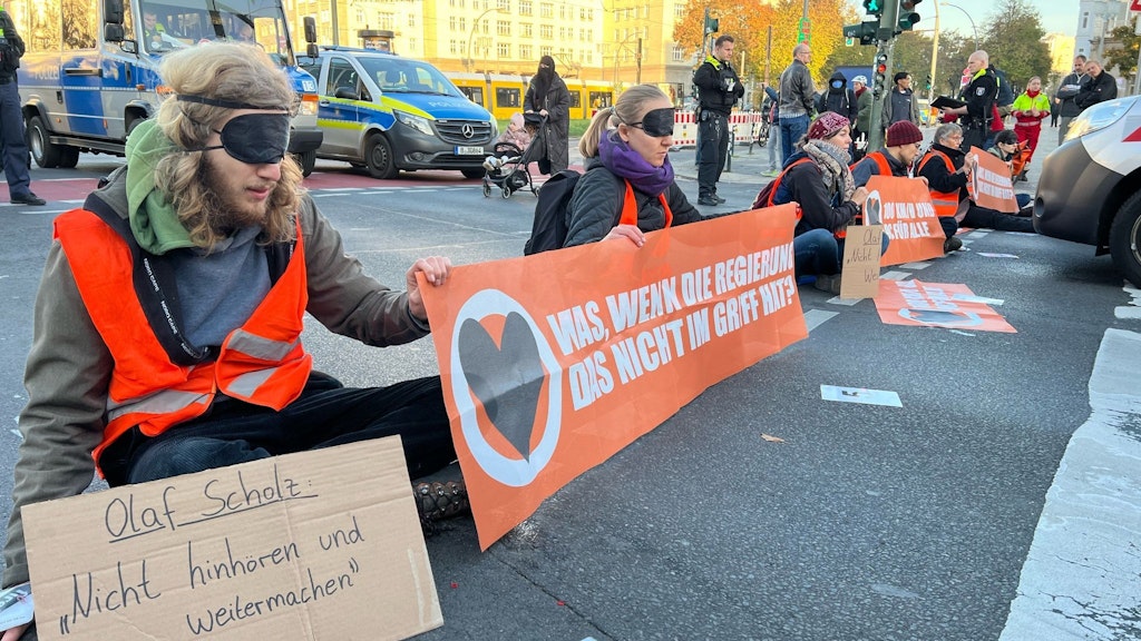 Klima-Aktivisten blockieren hier am Frankfurter Tor eine Fahrbahn, haben sich festgeklebt.