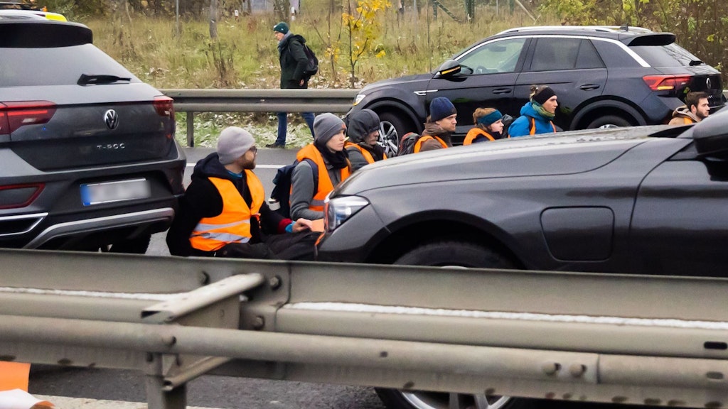 Teilnehmer eines Klimaprotests blockieren auf der A113 kurz vor der Ausfahrt zum Flughafen Berlin Brandenburg den Verkehr. 