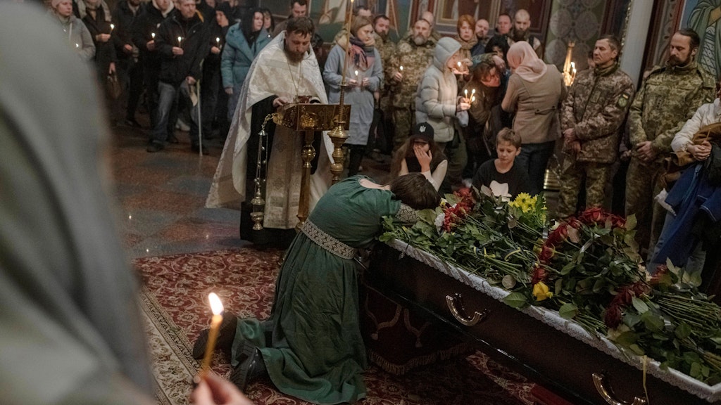 Eine Frau weint in Kiews Michaels-Kathedrale am Sarg ihres gefallenen Mannes.