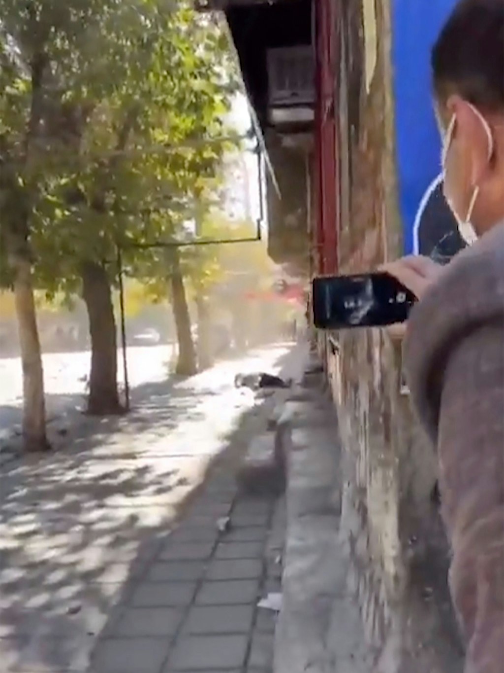 Ein Mann filmt in Dschawanrud, wie ein Mensch auf der Straße liegt, möglicherweise erschossen.