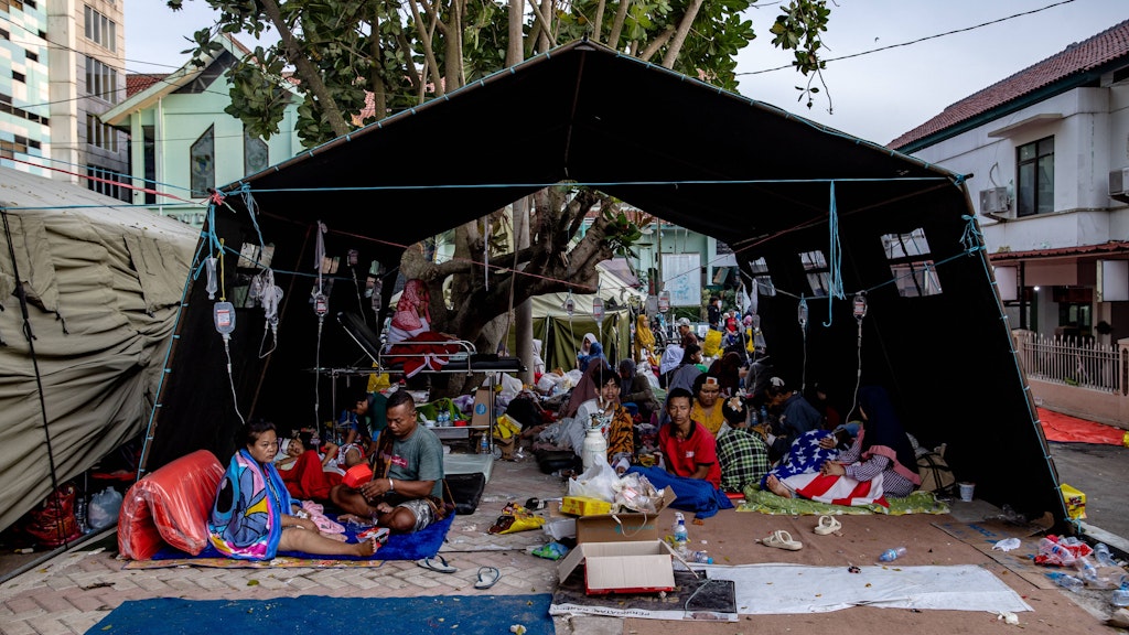 Indonesien: Menschen suchen außerhalb von Gebäuden Schutz unter einem Zelt. 