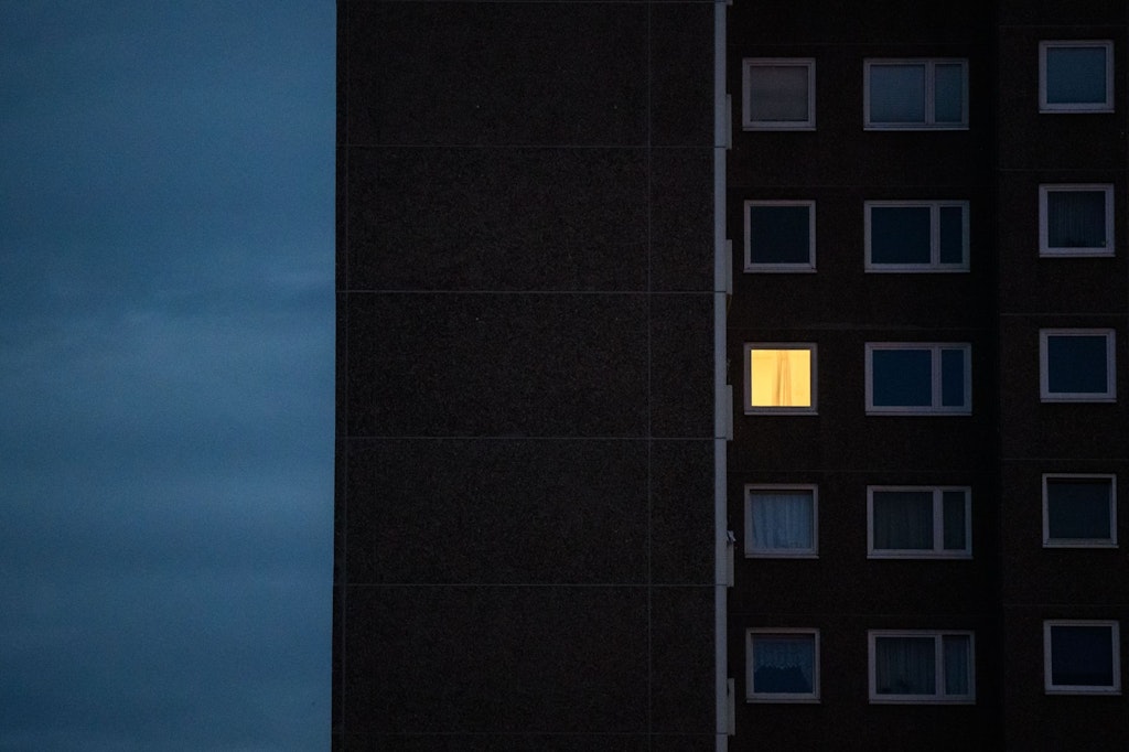 Licht brennt nur in einem Zimmer einer Wohnung in einem Mehrfamilienhaus (Symbolfoto). 