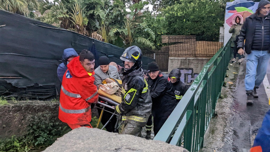 Feuerwehrleute tragen einen Mann aus dessen Haus auf Ischia.
