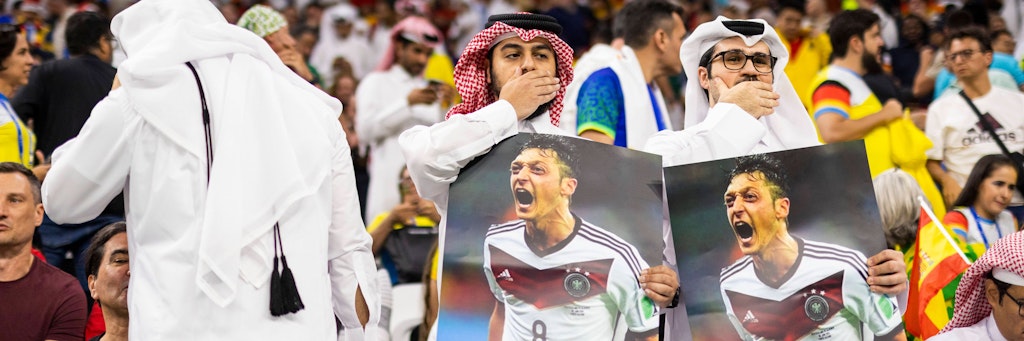 Einige Zuschauer protestierten beim Spiel Deutschland gegen Spanien mit Postern von Ex-Nationalspieler Mesut Özil. Dabei hielten sie sich die Hand vor dem Mund.