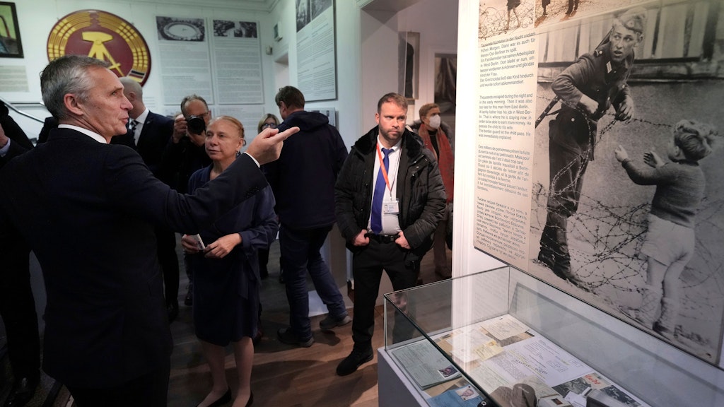Jens Stoltenberg zeigt auf ein Fotos von der Berliner Mauer. 