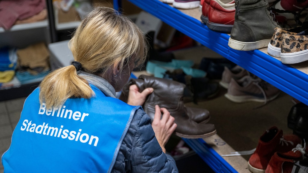 PRODUKTION - 28.11.2022, Berlin: Eine Mitarbeiterin der Berliner Stadtmission sortiert in der Kleiderkammer gespendete Schuhe und räumt sie in Regale ein. 