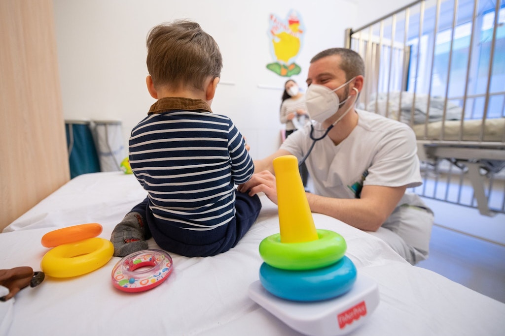 Ein Arzt untersucht in einer Kinderklinik ein Kind, derzeit sind die Einrichtungen völlig überlastet.