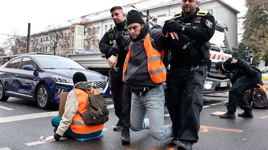 Polizisten tragen Klima-Kleber von der Kreuzung. Mit 200 Beamten wollen die Ordnungshüter nun in der kommenden Woche Störungen verhindern. Verdeckte Beamte sind mit im Einsatz.
